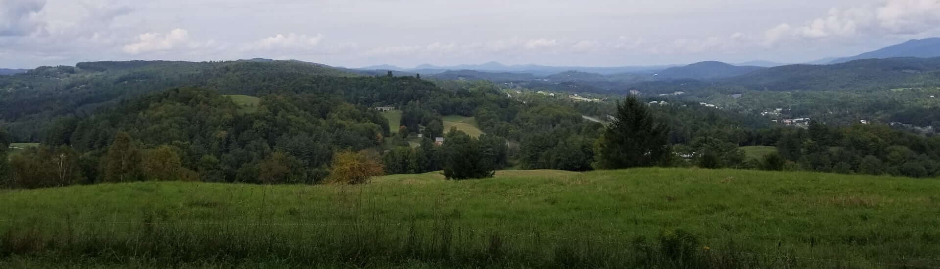 A panoramic view of rolling green hills under a cloudy sky.
